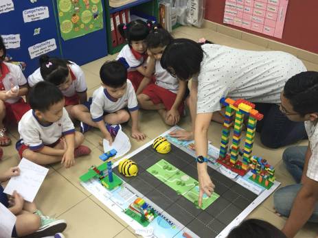 Crianças de quatro anos brincam com o BeeBot, abelha-robô usada no ensino de programação, em Cingapura. IDA 